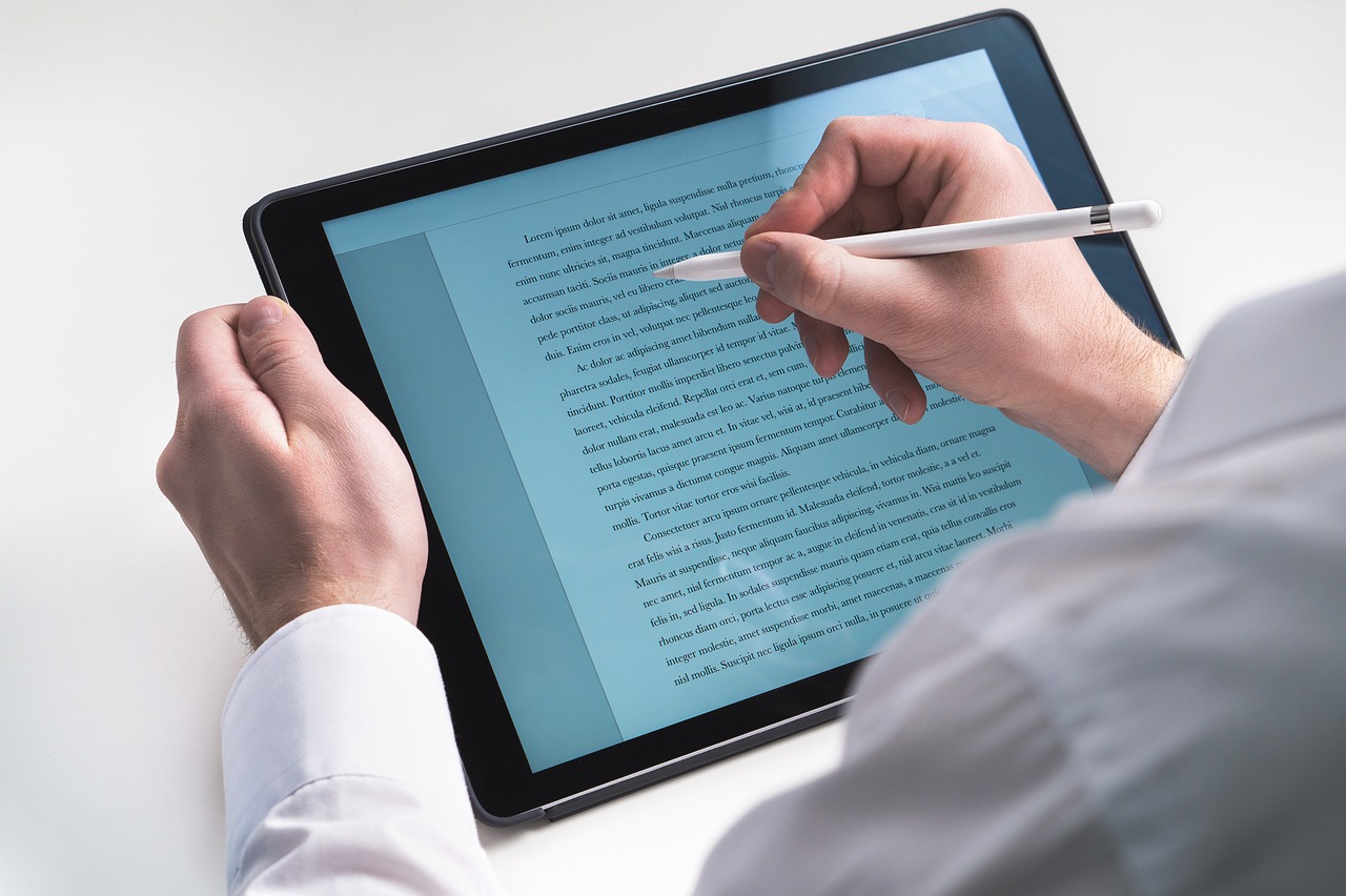 A man writing with an apple pen and ipad