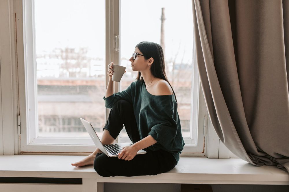 The girl by window with computer and coffee